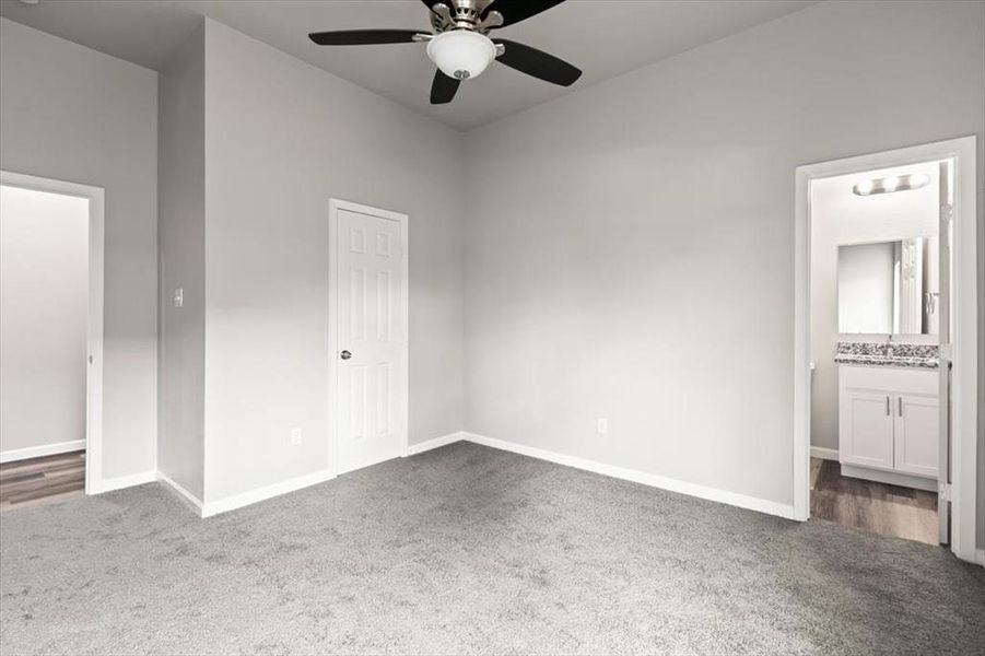 Bedroom featuring ensuite bathroom, ceiling fan, sink, carpet floors, and a closet