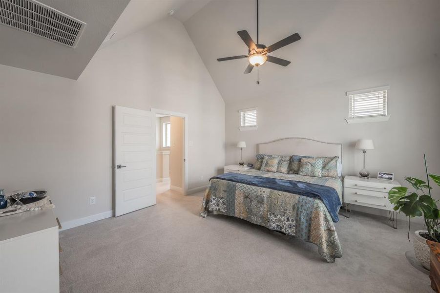 Carpeted bedroom featuring high vaulted ceiling and a ceiling fan
