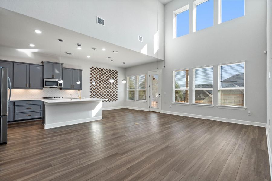 Double-height walls and clean-lined wood flooring anchor this sun-drenched, open-concept living area.