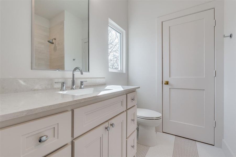 Bathroom featuring vanity, toilet, tile patterned flooring, and a shower