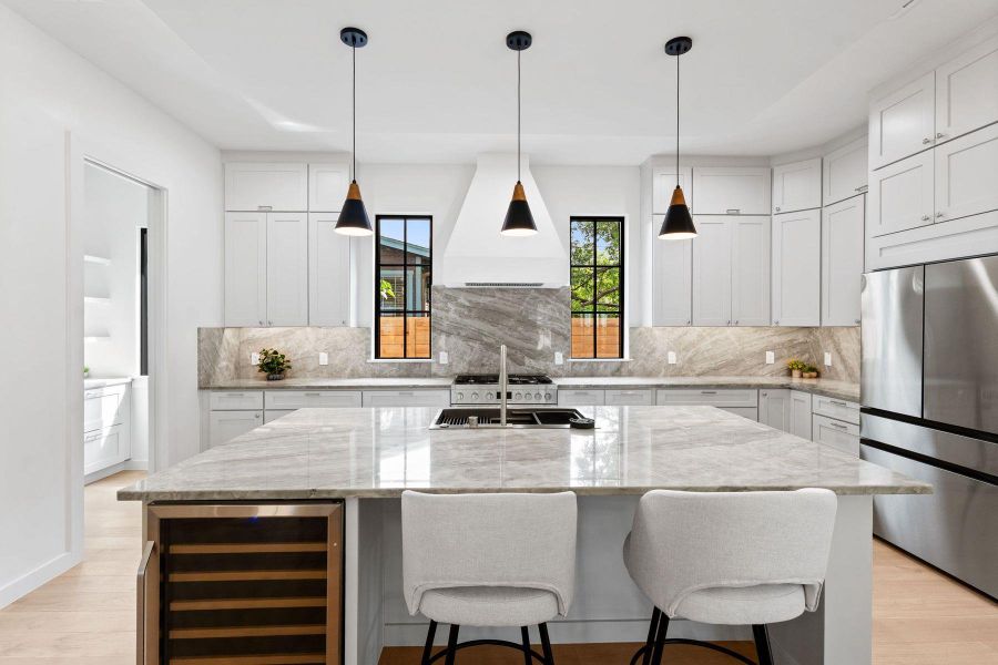 Elegant kitchen featuring a spacious island, high-end stainless steel appliances, and a sophisticated marble backsplash. Elegant kitchen featuring a spacious island, high-end stainless steel appliances, and a sophisticated marble backsplash.