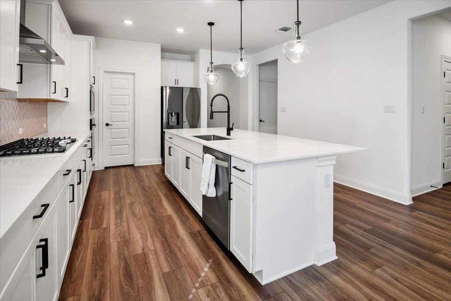 Modern kitchen features a substantial center island and rich wood-look flooring.