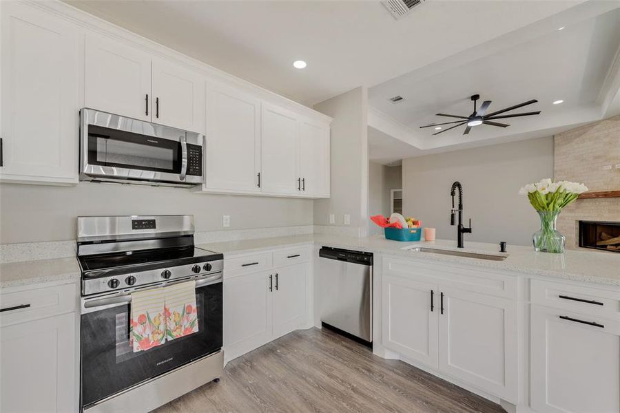 Kitchen featuring ceiling fan, white cabinetry, appliances with stainless steel finishes, light hardwood / wood-style floors, and sink