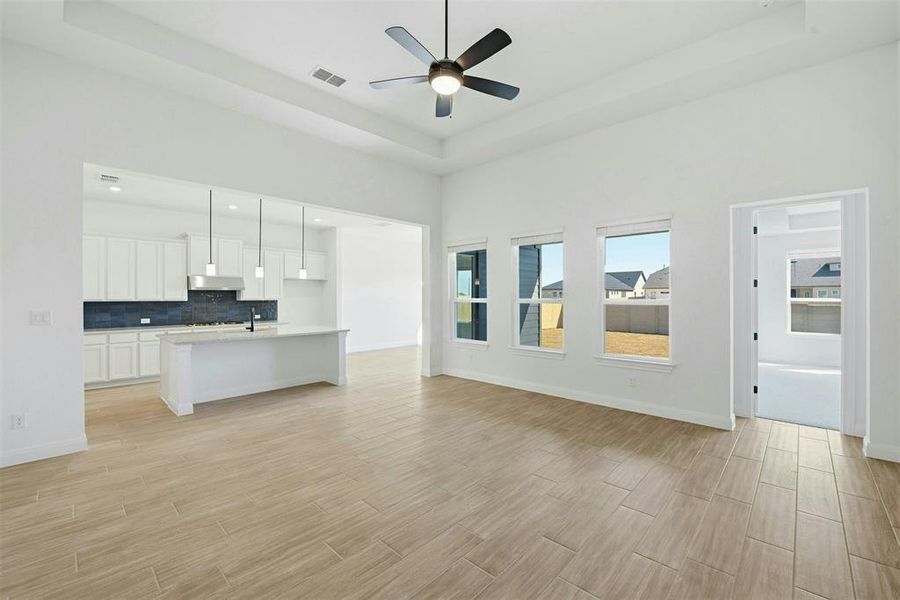 Open concept living space featuring wood-finish flooring, a tray ceiling, and a modern ceiling fan