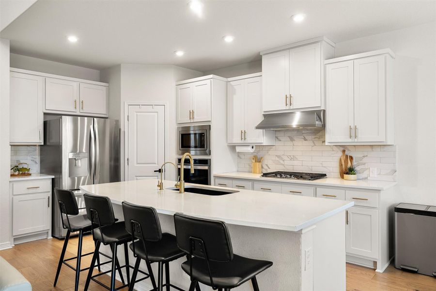 The center island with its breakfast bar creates an easy spot for quick meals, conversation, or extra prep space. Gourmet Kitchen features elegant backsplash, updated hardware, built in stainless steele appliances, walk-in pantry and gas stove with vent hood.