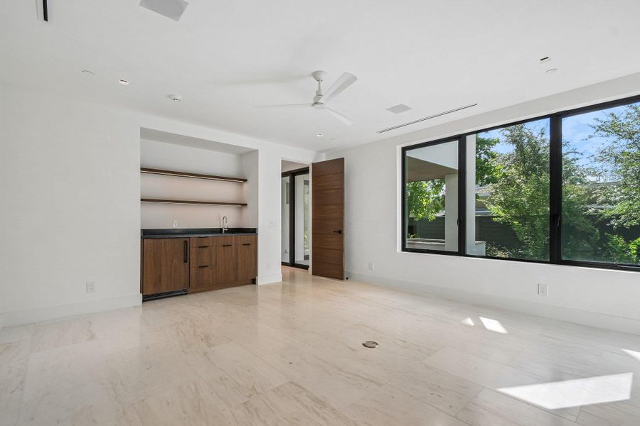 Polished tile flooring and black-framed windows highlight this versatile room with a built-in wet bar. Polished tile flooring and black-framed windows highlight this versatile room with a built-in wet bar.