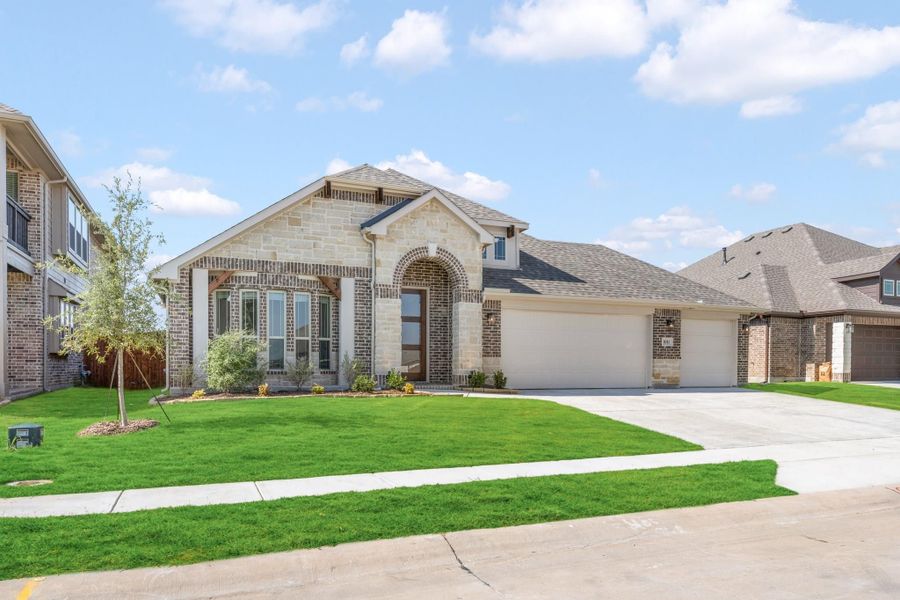Single-story brick and stone home with arched entry, two-car garage, and green front lawn Single-story brick and stone home with arched entry, two-car garage, and green front lawn