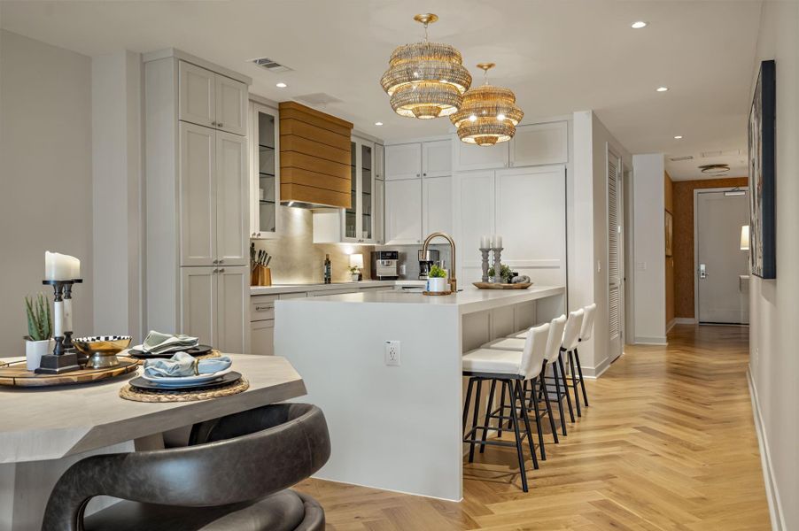 Herringbone hardwood floors extend from the dining area to a well-lit kitchen island with seating.