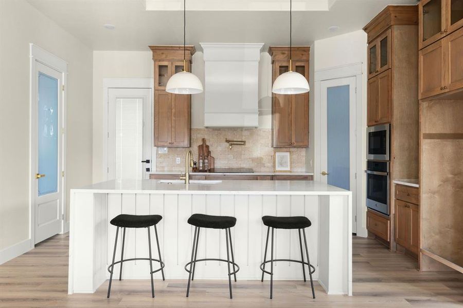 Kitchen with stainless steel appliances, hanging light fixtures, and a center island with sink