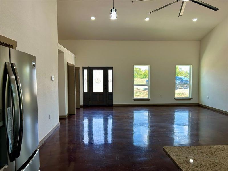 Entryway featuring finished concrete flooring, recessed lighting, a ceiling fan, and a high ceiling