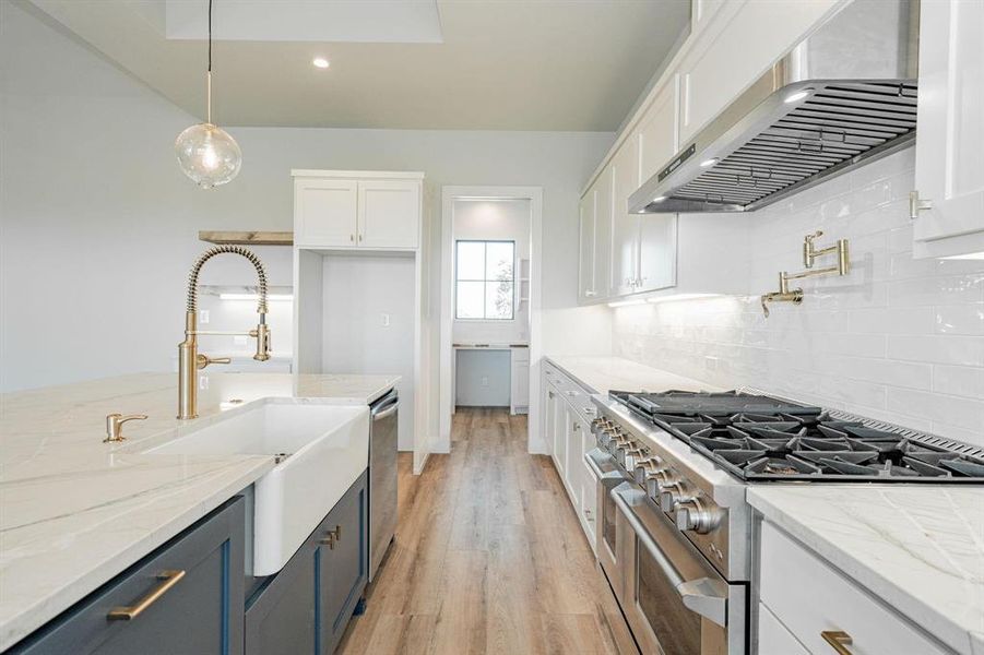 Example of builders Kitchen w white cabinetry, stainless steel appliances, light stone counters