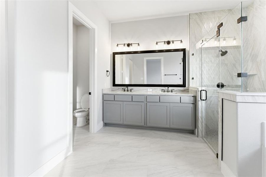 Full bath with a marble finish shower, double vanity, and light marble finish floors