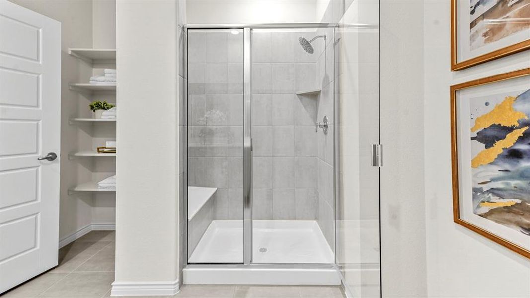 Walk-in shower featuring a glass enclosure, tiled walls, and a built-in bench