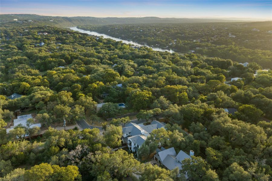 An aerial perspective reveals a private wooded estate nestled within a verdant landscape, with the river meandering nearby.