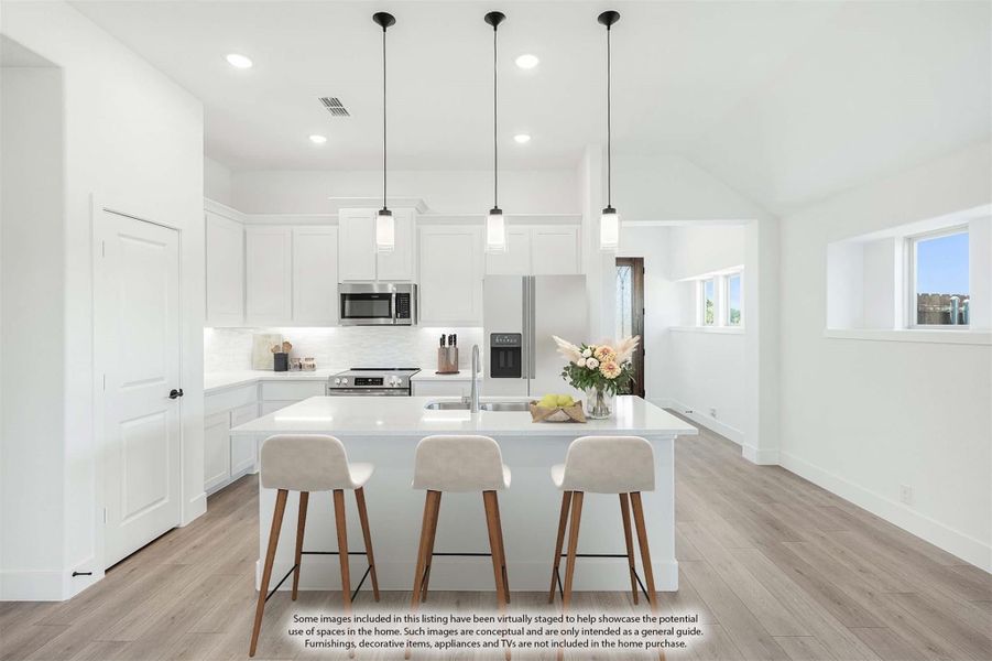 White kitchen with center island, three pendant lights, stainless appliances, and three bar stools on light wood floors