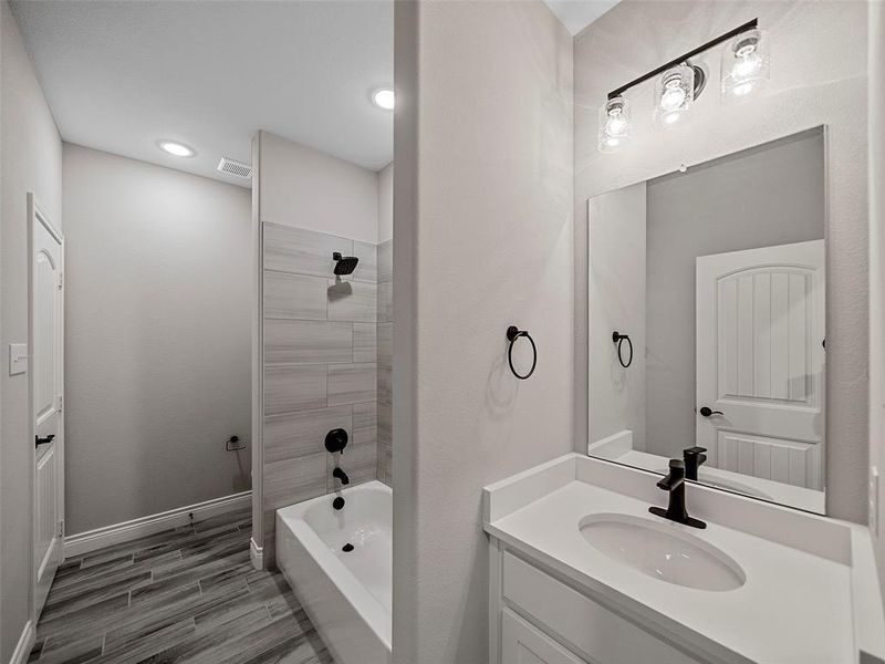 Full bathroom featuring tub / shower combination, vanity, wood finish floors, and recessed lighting Full bathroom featuring tub / shower combination, vanity, wood finish floors, and recessed lighting