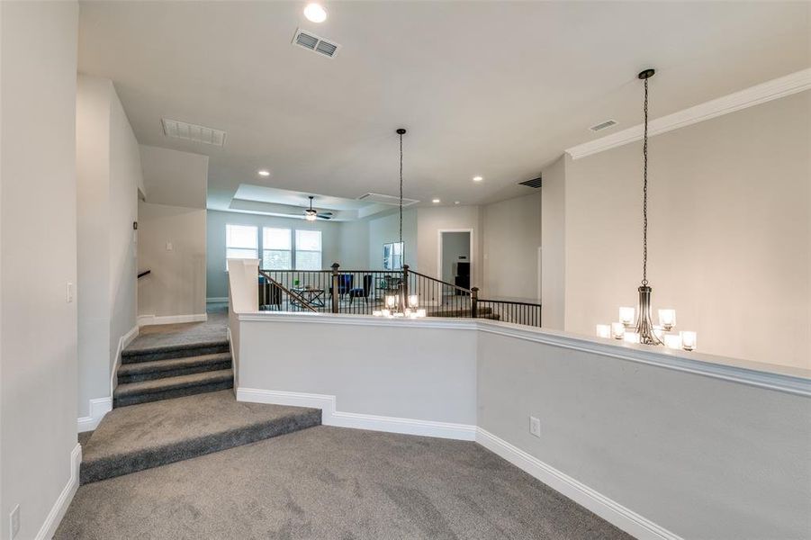 Loft space featuring crown molding, french doors to balcony, lofted ceiling, an inviting chandelier, and carpet