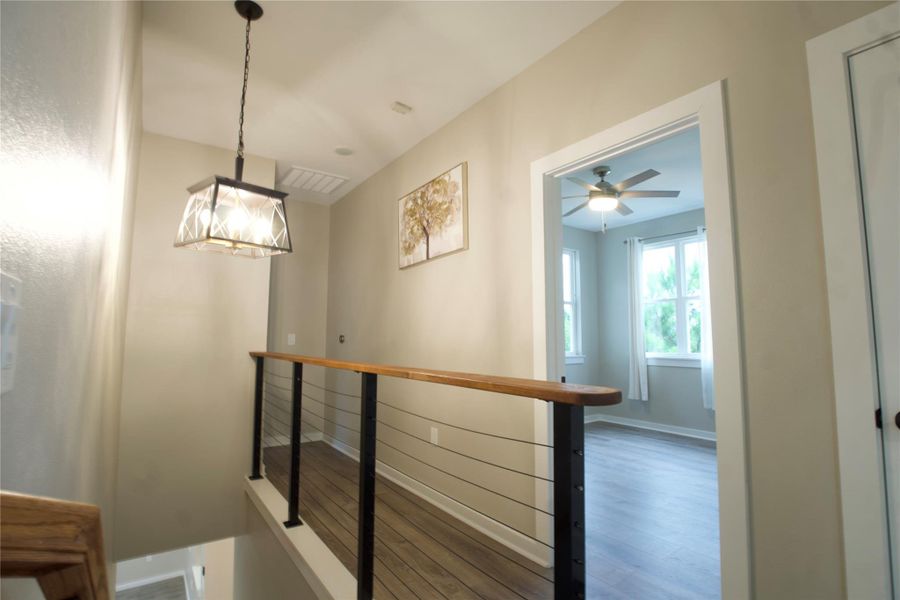 Hallway with wood finished floors and an upstairs landing