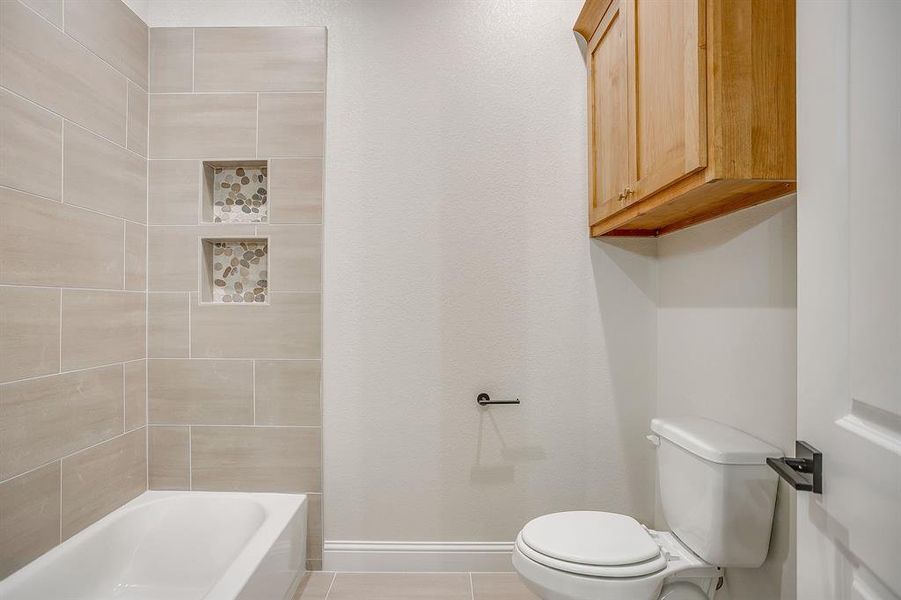 Bathroom with light tile patterned flooring and bathing tub / shower combination Bathroom with light tile patterned flooring and bathing tub / shower combination