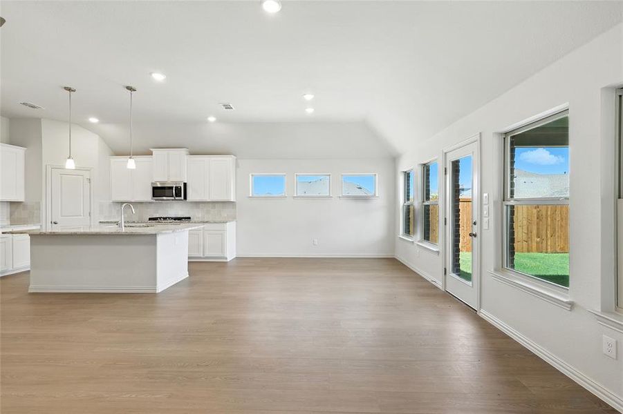 Kitchen with backsplash, white cabinets, recessed lighting, light wood-style floors, and a center island with sink Kitchen with backsplash, white cabinets, recessed lighting, light wood-style floors, and a center island with sink