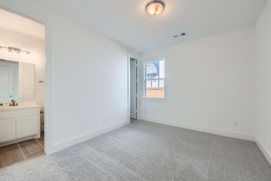 Unfurnished bedroom with light colored carpet, ensuite bath, and sink