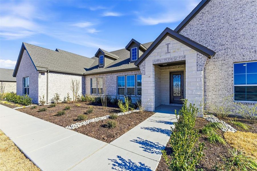 Entrance to property featuring brick siding and a shingled roof