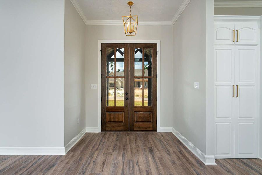 Entrance foyer with baseboards, ornamental molding, french doors, and dark wood-type flooring