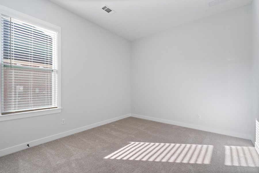White walls, carpet flooring, and a large window with blinds