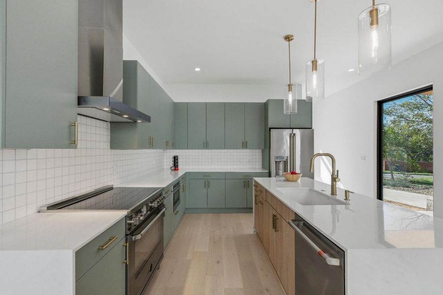 Kitchen featuring premium appliances, wall chimney range hood, light stone counters, and recessed lighting
