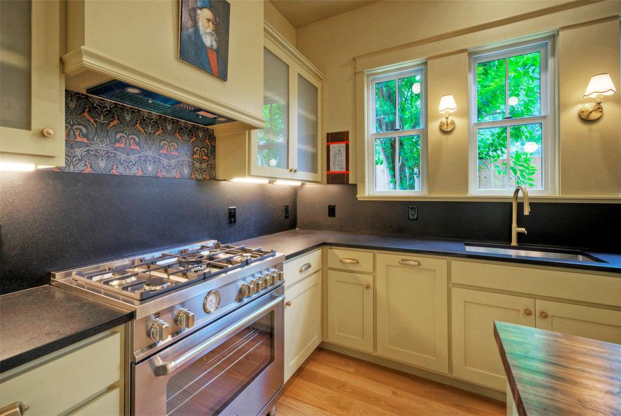 A chef's dream kitchen, offering a professional-grade gas range, deep basin sink, and plentiful under-cabinet illumination.