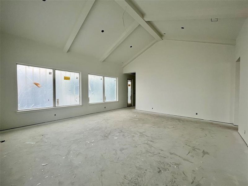 Empty room featuring beamed ceiling and high vaulted ceiling