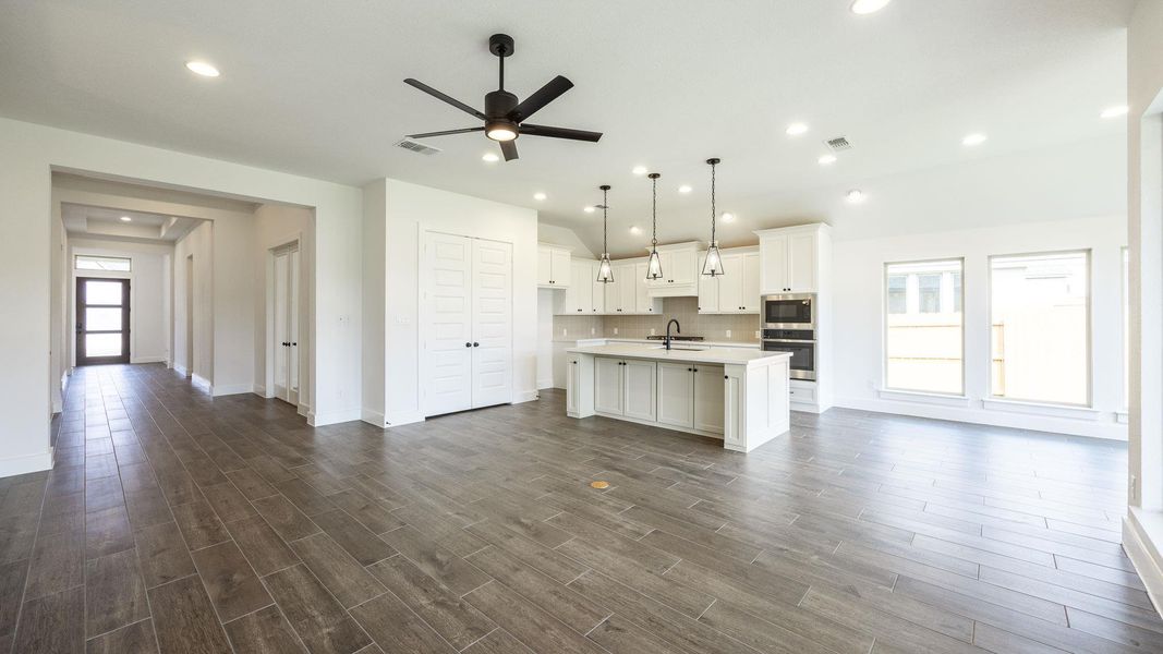 Kitchen featuring stainless steel appliances, a center island with sink, ceiling fan, open floor plan, and vaulted ceiling