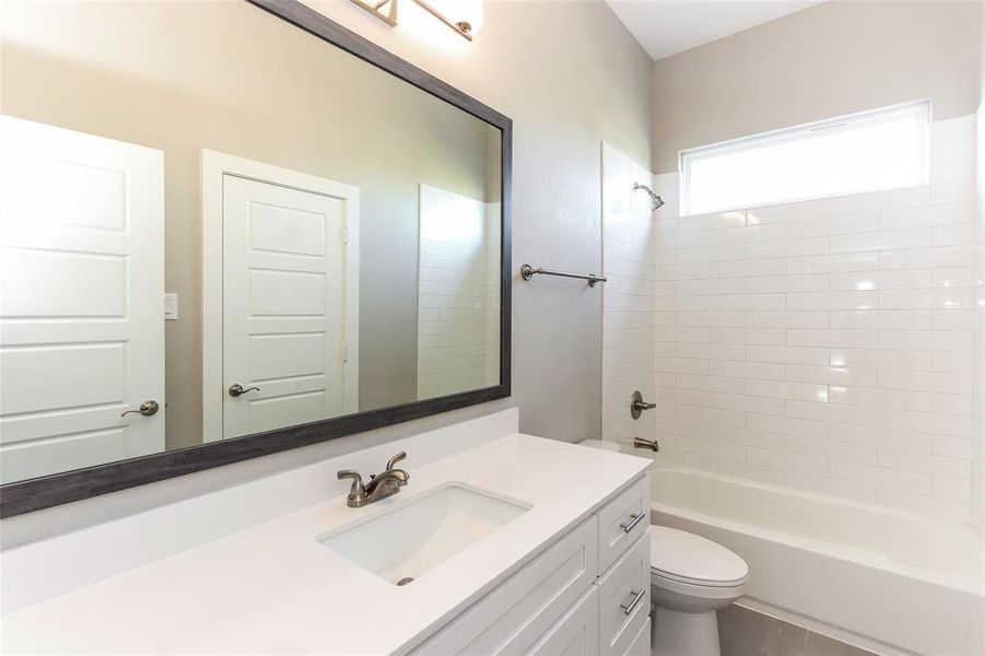 Full bathroom featuring tiled shower / bath, vanity, and toilet