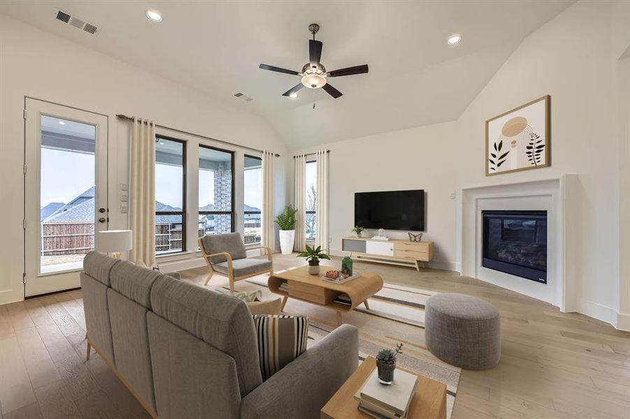 Virtually Staged - Living room with recessed lighting, lofted ceiling, a glass covered fireplace, light wood-style floors, and a ceiling fan