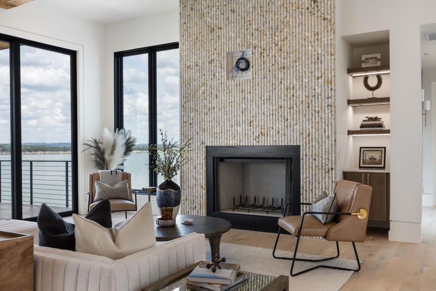 A spacious living area with floor-to-ceiling windows offers serene waterfront views and a stylish fireplace. A spacious living area with floor-to-ceiling windows offers serene waterfront views and a stylish fireplace.