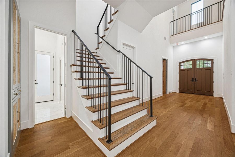 The wide gallery hall establishes elegant flow toward the home’s core living spaces. Tall ceilings emphasize openness, while continuous oak flooring adds warmth and cohesion. Iron railing introduces sculptural contrast. Raffia-inset cabinetry provides functional storage and textural depth, enhancing the home’s balance of refined design and everyday usability. *Previous Project*