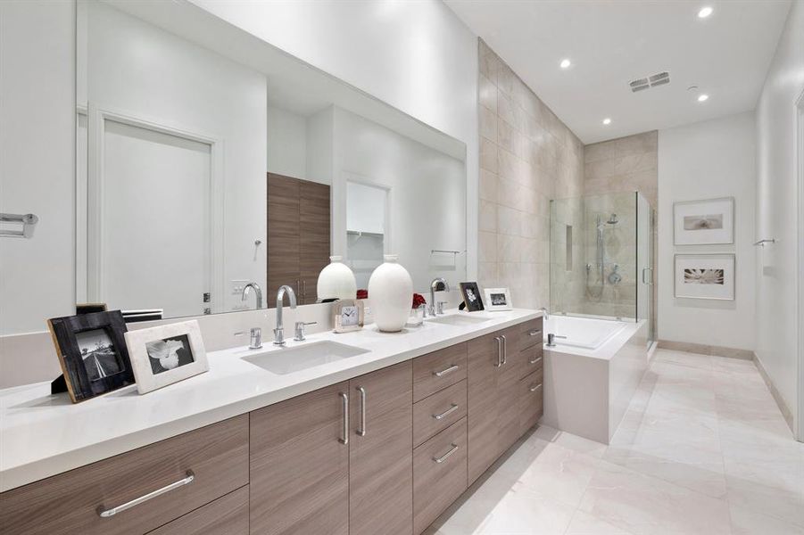 Primary en-suite bathroom with dual vanity, soaking tub and glass enclosed step-in shower.