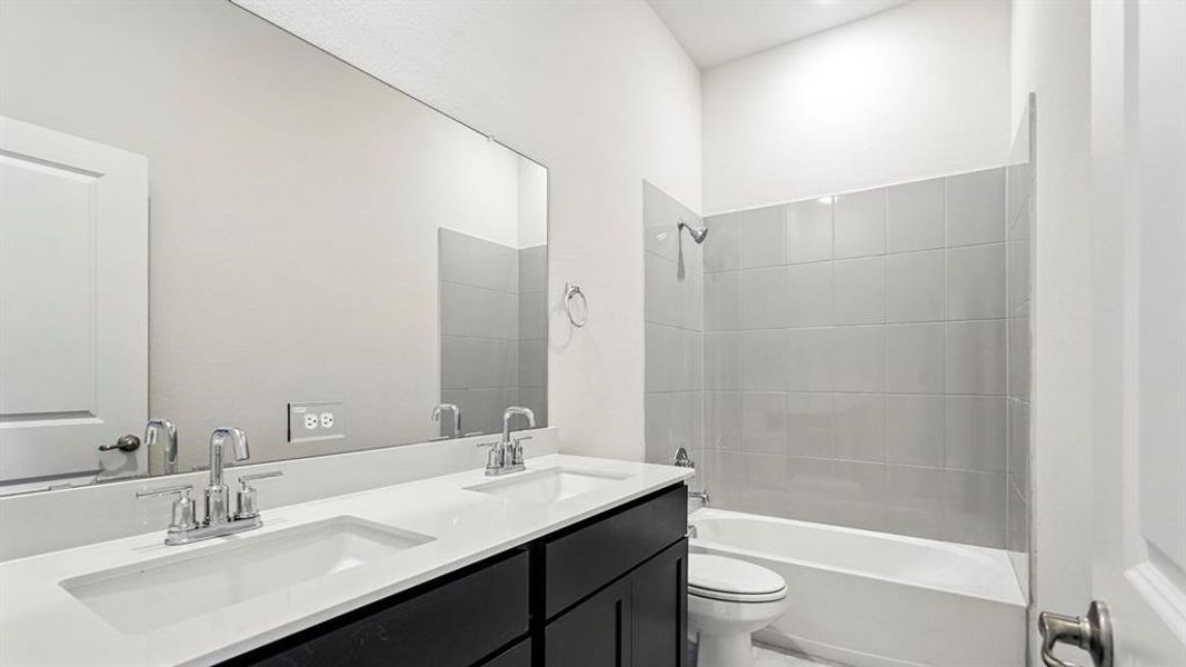 Bathroom featuring double vanity and shower / bathtub combination