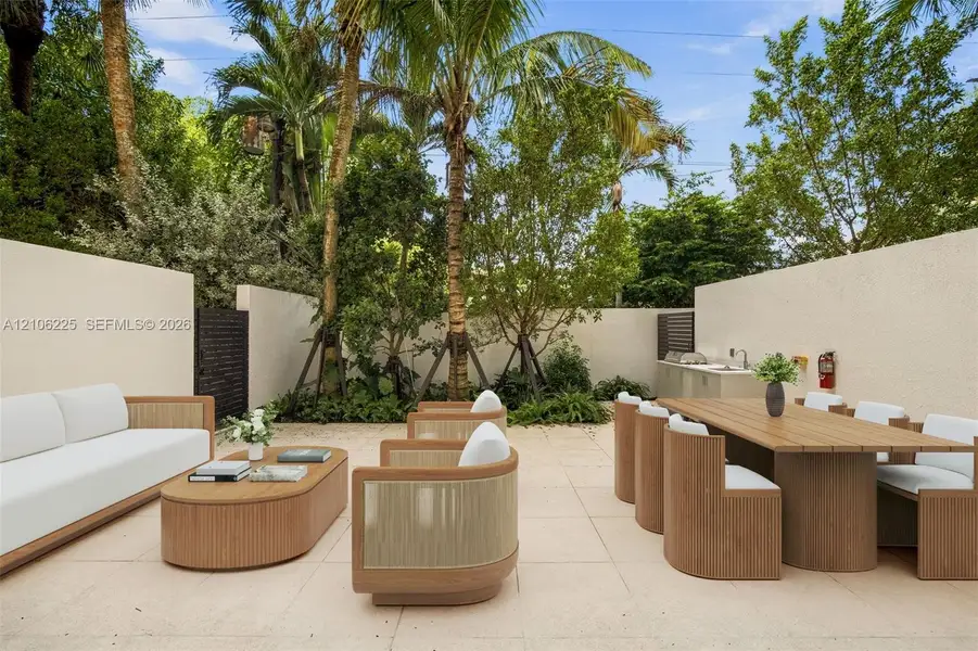Private courtyard featuring limestone-style paving, high perimeter privacy walls, mature palm trees, and an integrated outdoor kitchen area with a built-in sink Private courtyard featuring limestone-style paving, high perimeter privacy walls, mature palm trees, and an integrated outdoor kitchen area with a built-in sink