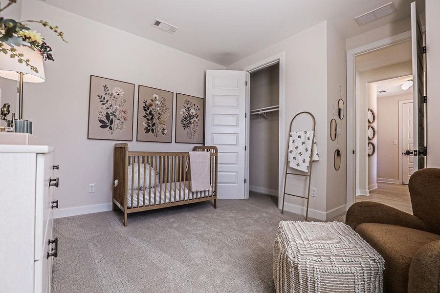 Bedroom featuring a crib, light carpet, and a closet