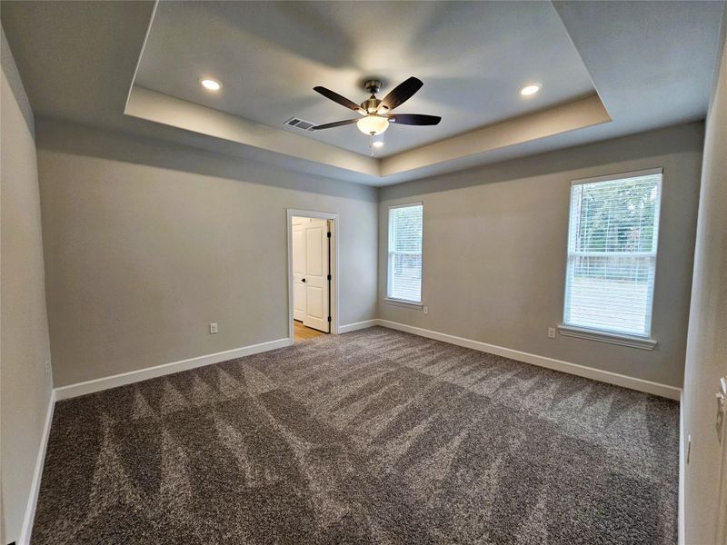 Unfurnished room with a raised ceiling, carpet flooring, recessed lighting, and a ceiling fan