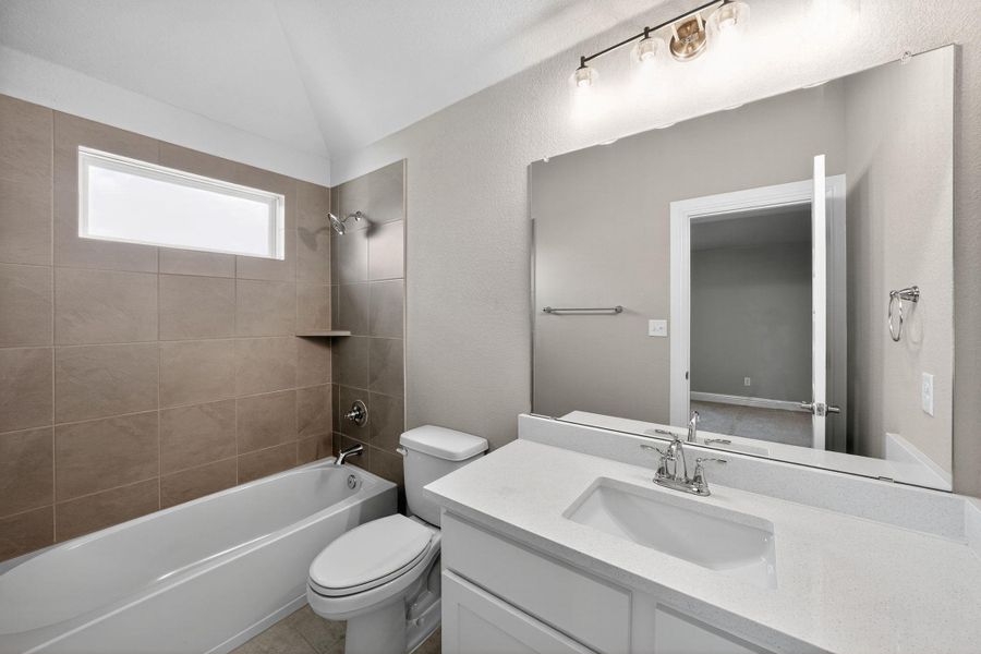 Bathroom with shower / bath combination, vanity, a textured wall, and lofted ceiling Bathroom with shower / bath combination, vanity, a textured wall, and lofted ceiling