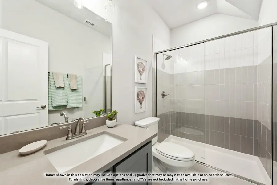 Bathroom with gray countertop vanity, glass-enclosed shower with tile walls, and white toilet. Bathroom with gray countertop vanity, glass-enclosed shower with tile walls, and white toilet.