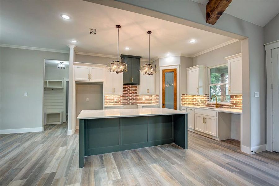 Kitchen with white cabinetry, a center island, and light wood-type flooring Kitchen with white cabinetry, a center island, and light wood-type flooring