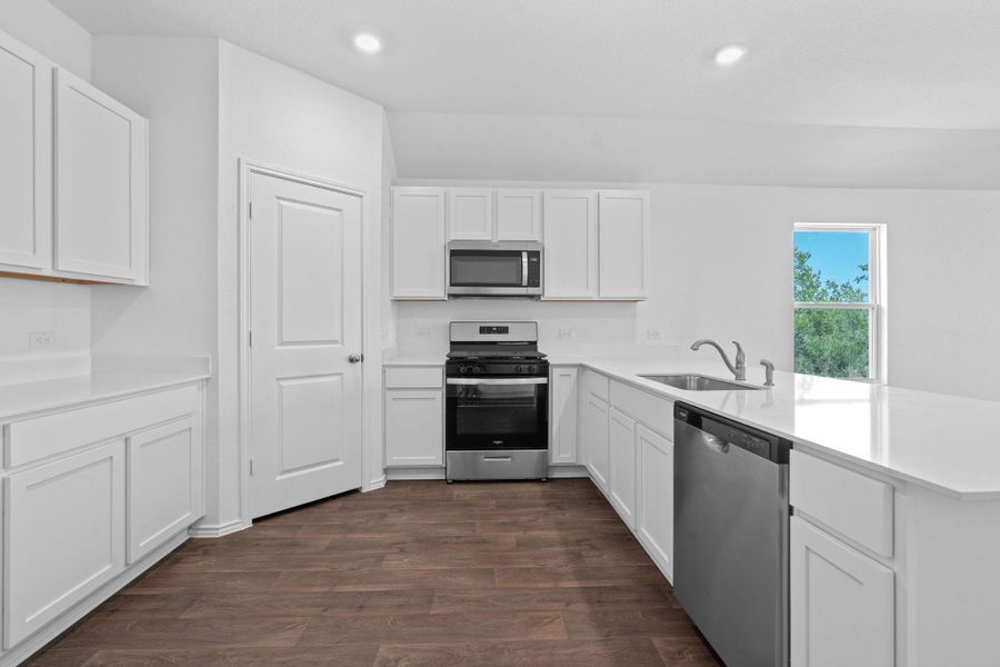 Kitchen with appliances with stainless steel finishes, white cabinets, dark wood finished floors, recessed lighting, and a peninsula Kitchen with appliances with stainless steel finishes, white cabinets, dark wood finished floors, recessed lighting, and a peninsula