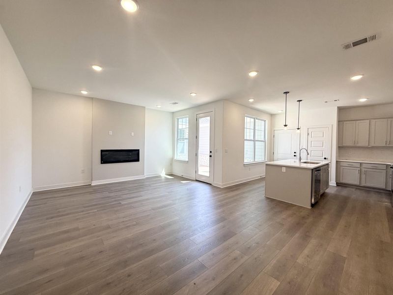 Unfurnished living room featuring recessed lighting, dark wood-style flooring, and a glass covered fireplace