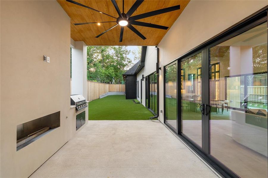 Covered patio featuring an integrated grill station, wood-finish ceiling with a ceiling fan, and extensive sliding glass doors Covered patio featuring an integrated grill station, wood-finish ceiling with a ceiling fan, and extensive sliding glass doors
