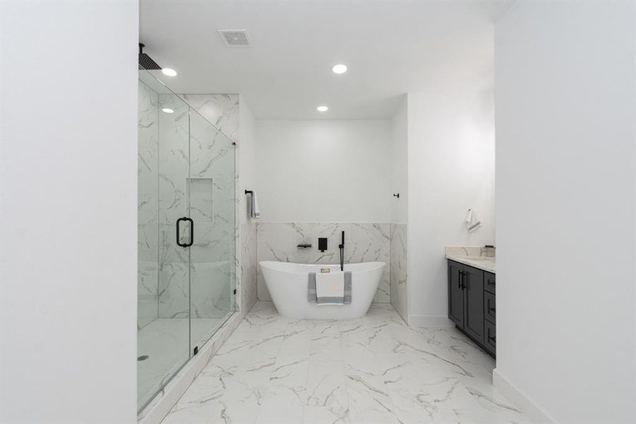 This primary bathroom with a separate shower and soaker tub exudes relaxation.  This shower has a rain shower head and frameless shower.