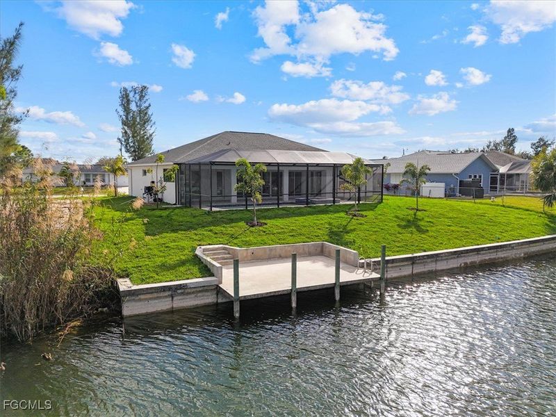 Dock area with a water view, a yard, and screen enclosure
