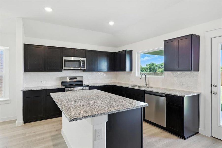 Kitchen featuring stainless steel appliances, light wood-type flooring, decorative backsplash, light stone countertops, and recessed lighting Kitchen featuring stainless steel appliances, light wood-type flooring, decorative backsplash, light stone countertops, and recessed lighting